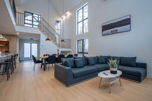 a living room with a blue couch and a table at Le Greenwood 2 - Sauna - Spa - Mountain View in Saint-Faustin