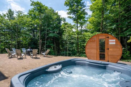 a hot tub in the middle of a backyard with a wooden cabin at Le Greenwood 2 - Sauna - Spa - Mountain View in Saint-Faustin
