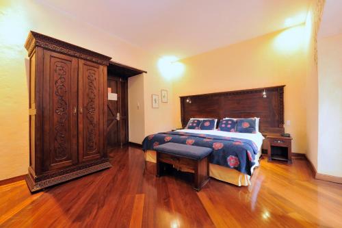 a bedroom with a bed and a large wooden cabinet at La Casona de la Ronda Hotel Boutique in Quito