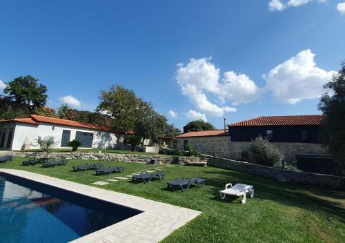 a backyard with a pool and tables and chairs at Quinta de Ramil in Vieira do Minho