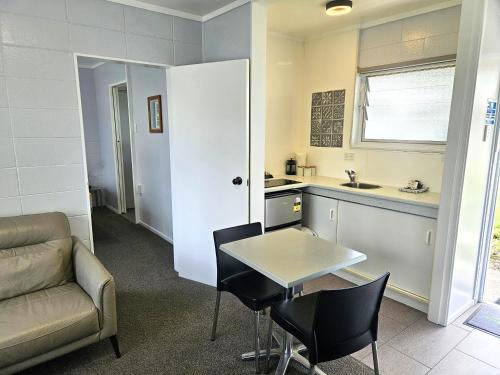 Tarawera River Lodge Motel في Kawerau: غرفة معيشة مع أريكة وطاولة ومطبخ