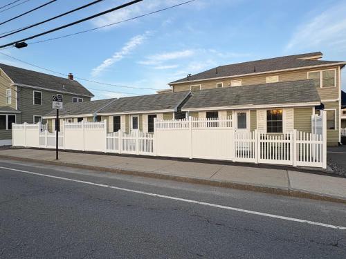 a white fence in front of a house at Moontide Motel, Apartments, and Cabins in Old Orchard Beach