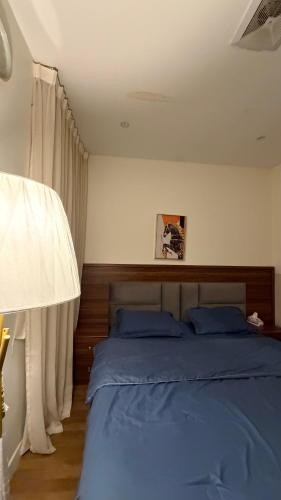 Schlafzimmer mit einem Bett mit blauer Bettwäsche und Vorhängen in der Unterkunft شقه فندقيه غرفة نوم وغرفة معيشه in Al Kharj