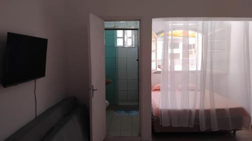 una camera da letto con un letto, una finestra e una televisione di Pousada a São Vicente