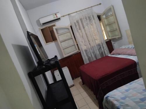 una piccola stanza con due letti e una finestra di Pousada a São Vicente