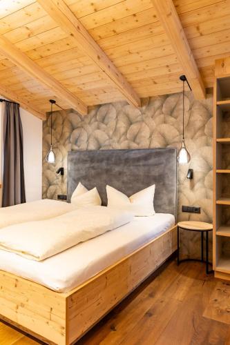 a bedroom with a large bed with a stone wall at Schulhaus Tirol in Zell am Ziller