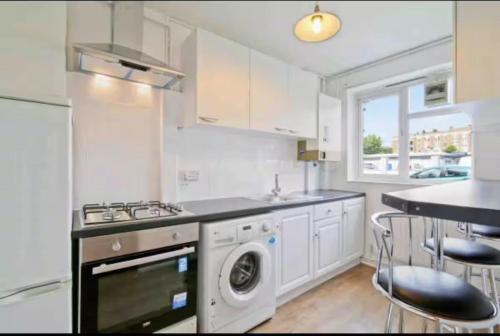 una cucina bianca con lavatrice e asciugatrice di Barker House a Londra