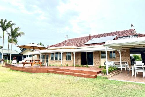 a house with a deck with a table and an umbrella at Crystal Palms - Oceanstays - Riverside in Yamba