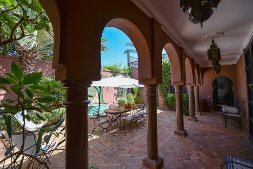un patio esterno con tavolo, sedie e ombrellone di Maison Ayda a Marrakech