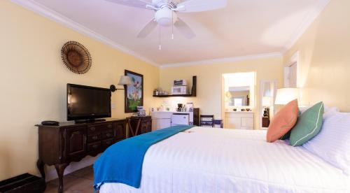 a bedroom with a white bed and a flat screen tv at The Caribbean Court Boutique Hotel in Vero Beach