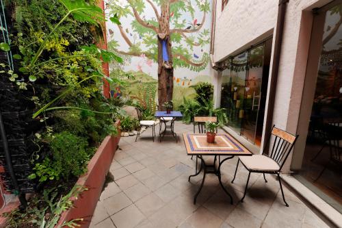 a patio with tables and chairs and a tree painted on the wall at La Casona de la Ronda Hotel Boutique in Quito