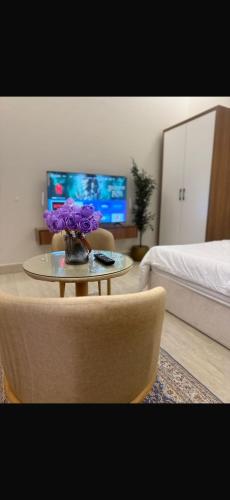 a living room with a table with purple flowers on it at استديو مودرن فندقي in Al Kharj