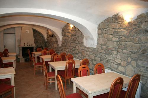 a restaurant with tables and chairs and a stone wall at Penzion Javořice in Telč