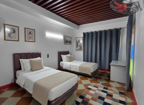 ein Schlafzimmer mit zwei Betten und einem Fernseher darin in der Unterkunft Riad Imperial Atlas in Meknès