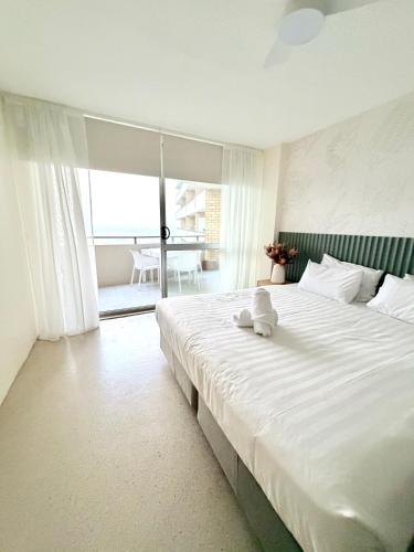 a white bed with a teddy bear sitting on it at 706TheSands Beachfront Apartment at the centre of Surfers Paradise in Gold Coast