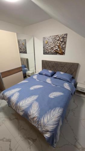 a bedroom with a blue bed with blue pillows at Flower Apartman in Veternik