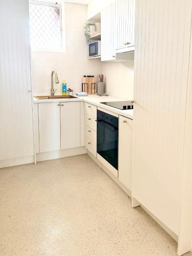a white kitchen with a sink and a stove at 706TheSands Beachfront Apartment at the centre of Surfers Paradise in Gold Coast