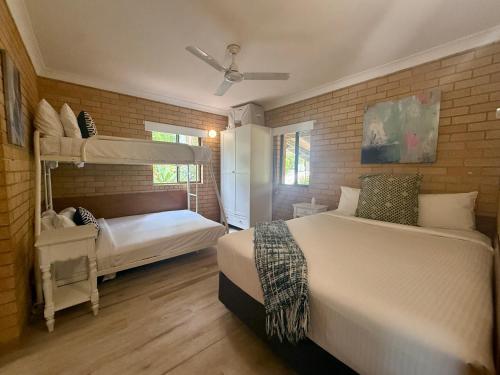 Un dormitorio con dos literas y una pared de ladrillo. en Tropic Oasis by Charlesworth, en Coffs Harbour