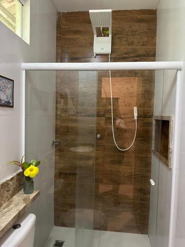 a shower with a glass door in a bathroom at Aruana Suites com Cafe da manha,Piscina, Reserva Natural da Sapiranga 5km da Vila de Praia do Forte in Castelo da Tôrre