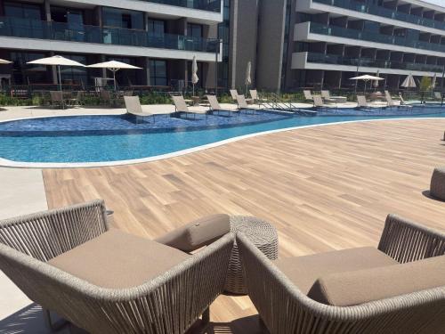 ein Pool mit Liegestühlen und Sonnenschirmen neben einem Gebäude in der Unterkunft Beach Class Summer Residence in Porto De Galinhas