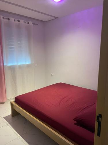 een rood bed in een witte kamer met een raam bij Résidence Picasso in Casablanca
