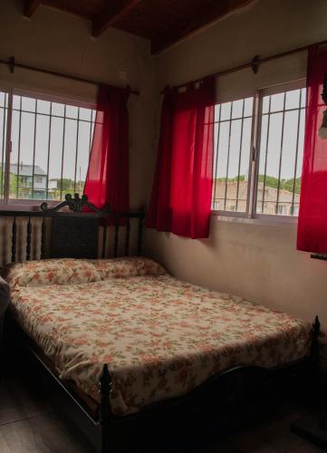a bedroom with a bed with red curtains and windows at El Dorado in Mar del Plata