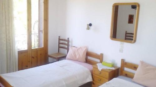 Loutrópolis ThermísにあるApartments Villa Myrtoのベッドルーム1室(ベッド2台、鏡、窓付)