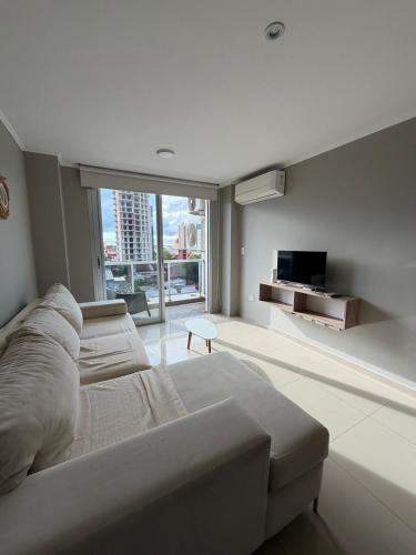 Un dormitorio blanco con una cama grande y un televisor. en Edif Alarif Piso 7F, en Posadas