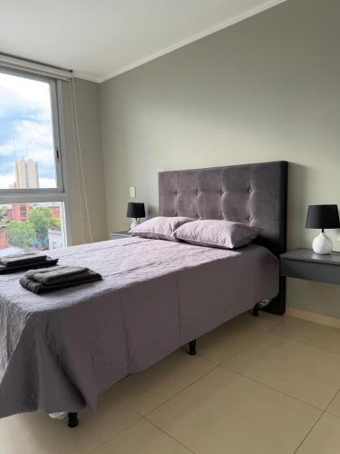 Un dormitorio con una cama grande con una ventana grande. en Edif Alarif Piso 7F, en Posadas
