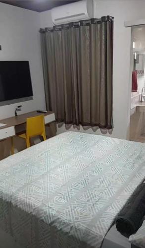 una camera da letto con un letto e una scrivania con una televisione di Flat luxo e tranquilidade a Volta Redonda