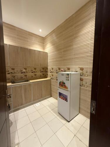 a kitchen with a white refrigerator and wooden cabinets at مارينا جده للشقق المخدومه in Jeddah