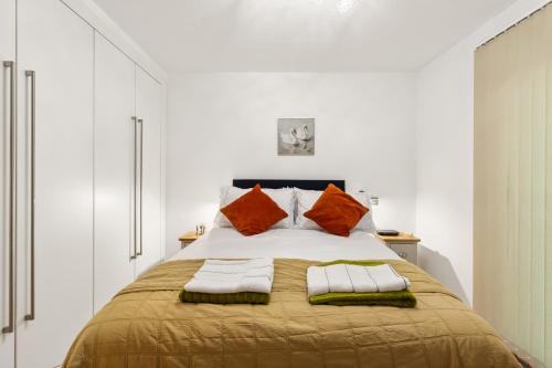 a bedroom with a large bed with orange pillows at Khayat Homes - The Ford in Chelmsford