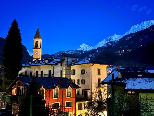 un edificio con una iglesia con una torre de reloj en Bernina House, en Chiesa in Valmalenco