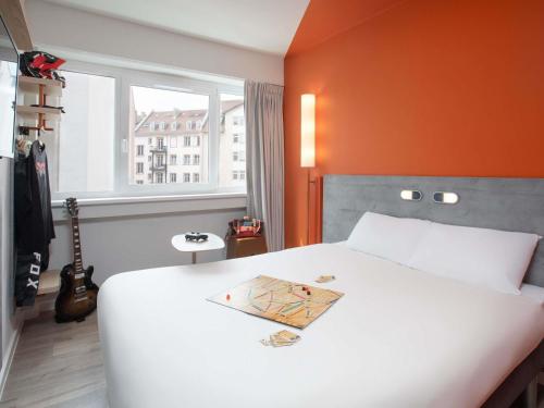 um quarto com uma cama branca e uma parede laranja em Ibis Budget Strasbourg Centre Republique em Estrasburgo