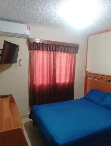 a bedroom with a blue bed and a red curtain at Departamento Morrocoy Ixtapa in Ixtapa