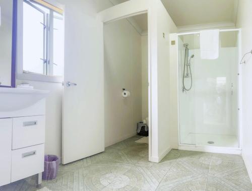 een badkamer met een douche en een wastafel bij Natura Nikao Beachside 3BM Villa in Avarua