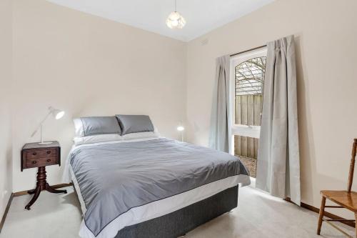 ein weißes Schlafzimmer mit einem Bett und einem Fenster in der Unterkunft Beach Street in Queenscliff