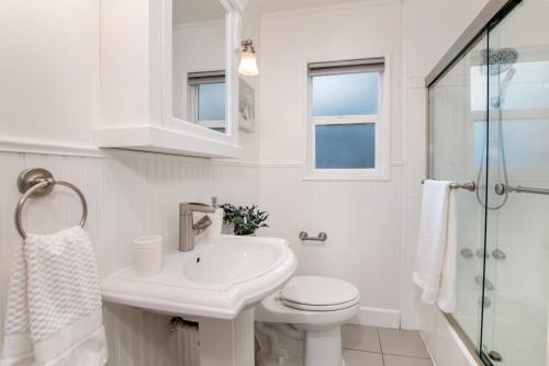 Un baño blanco con inodoro y lavabo. en Downtown San Jose Airport Shared Home, en San José