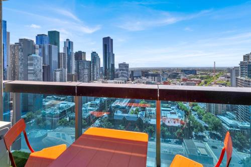 a balcony with orange chairs and a view of a city at Nook Melbourne Apartments : Jane Bell Lane - Melbourne CBD in Melbourne
