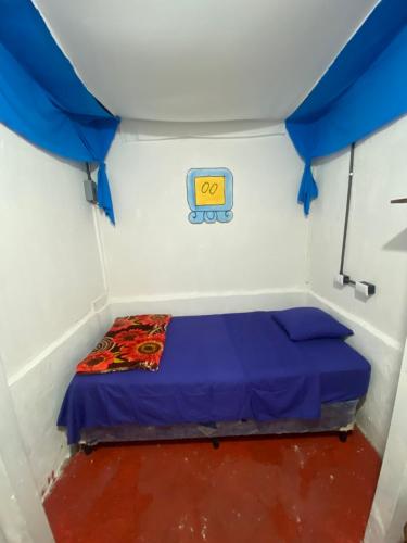 Una cama pequeña en una habitación con dosel azul. en Gran Colibrí Adventure Park, en San Pedro La Laguna