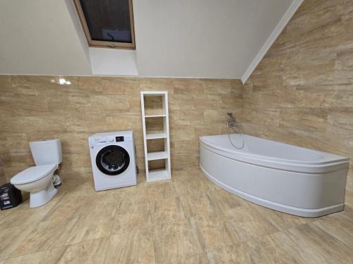 een badkamer met een badkuip, een wasmachine en een toilet. bij Royal Residence Uzhhorod in Oezjhorod