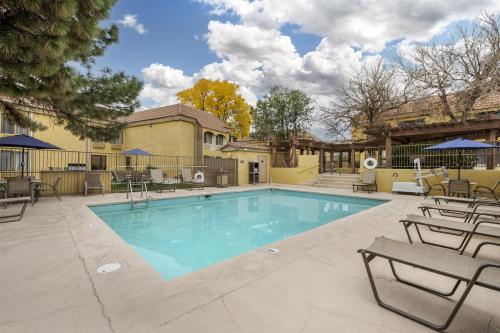 a swimming pool with chairs and a table at Best Western Airport Albuquerque InnSuites Hotel & Suites in Albuquerque