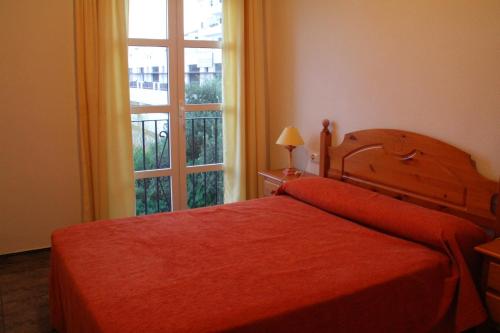 een slaapkamer met een rood bed en een raam bij Hostal El Mirador in Vejer de la Frontera
