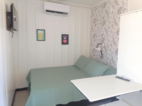 a small room with a bed and a desk at Studio Borboletas de luz in Bombinhas