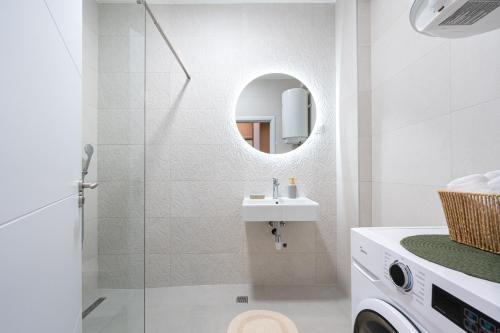 ein weißes Badezimmer mit Waschbecken und Spiegel in der Unterkunft Quince Apartments in Podgorica