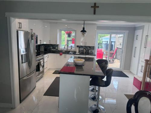 eine Küche mit einem Kühlschrank aus Edelstahl und einem Tisch in der Unterkunft Amazing Home away from Home in Sainte-Catherine