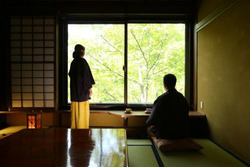 un hombre y una mujer mirando por una ventana en 志賀高原 白い温泉 渓谷の湯, en Yamanouchi