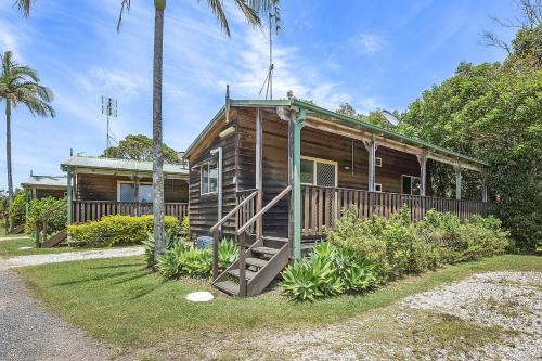 a wooden house with a porch and palm trees at Reflections Nambucca Heads - Holiday Park in Nambucca Heads
