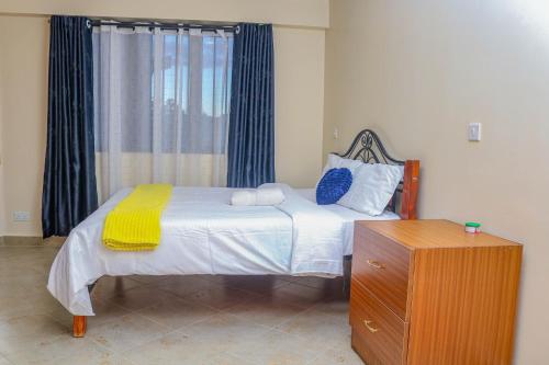a bedroom with a bed and a dresser and a window at Nanyukihomes3 in Nanyuki