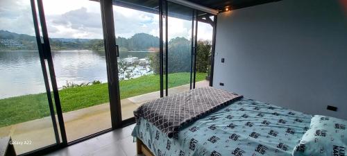 een slaapkamer met een bed en een groot raam bij Villa Lake Blue in El Peñol